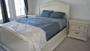 A bed with a white headboard and a bedside table with a drawer.