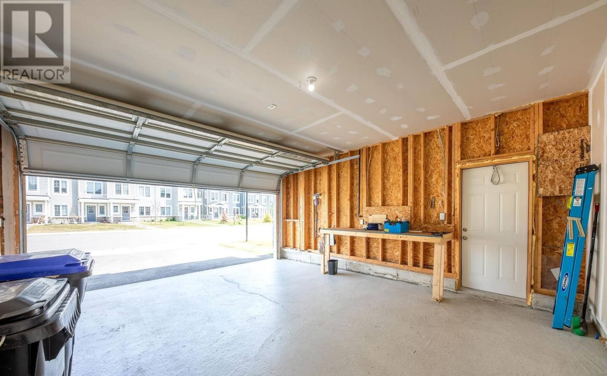 A garage with a workbench, tools, and a ladder.