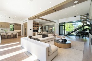 Ein großzügiger Wohnbereich mit einer großen Couch, einem Couchtisch und einer Treppe zu einem Balkon.