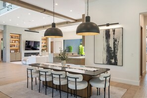Eine moderne Küche mit Kochinsel, Barhocker und Pendelleuchten.