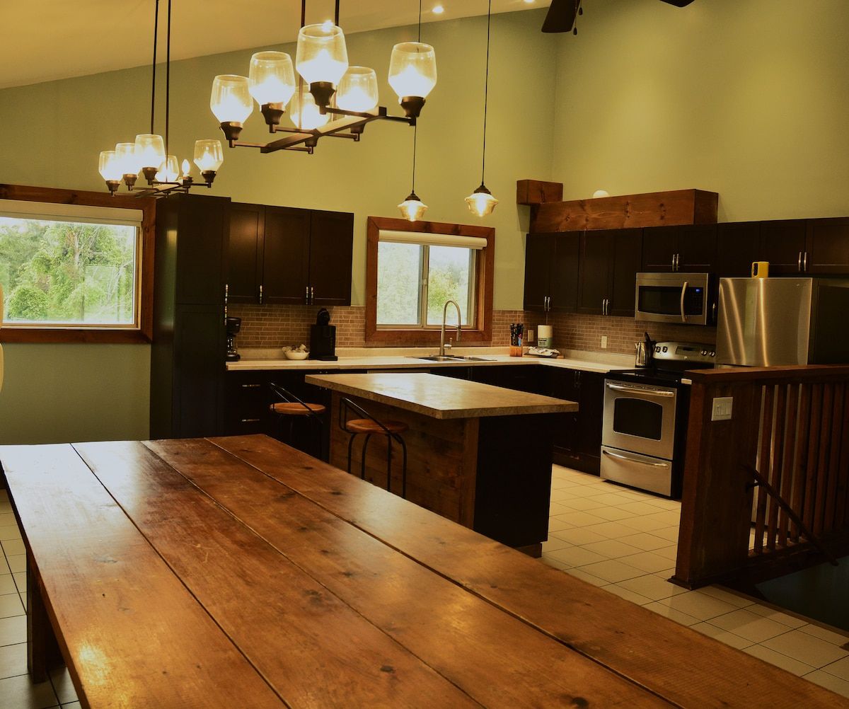 Une cuisine dotée d’un îlot central, de meubles en bois, d’un réfrigérateur en acier inoxydable et d’un luminaire suspendu.
