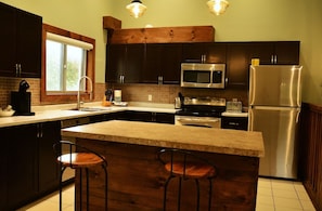 A modern kitchen with dark wood cabinets, stainless steel appliances, and a central island with bar stools. - Blue Mountains Chalet | Sleeps 18 | Hot Tub & BBQ I 1 Minute Drive to Village (The Blue Mountains)