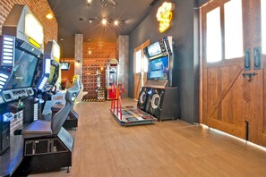 Ein Spielbereich mit mehreren Arcade-Automaten, einer Jukebox und einem großen Bildschirmfernseher.