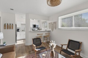 A modern kitchen with white cabinets, a microwave, and a coffee maker. There is a dining area with two wooden chairs and a glass table. - Cozy Stylish Apt in Omaha`s Medical District! (Omaha)