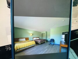 Una habitación de hotel con dos camas, un escritorio, una silla y un refrigerador.
