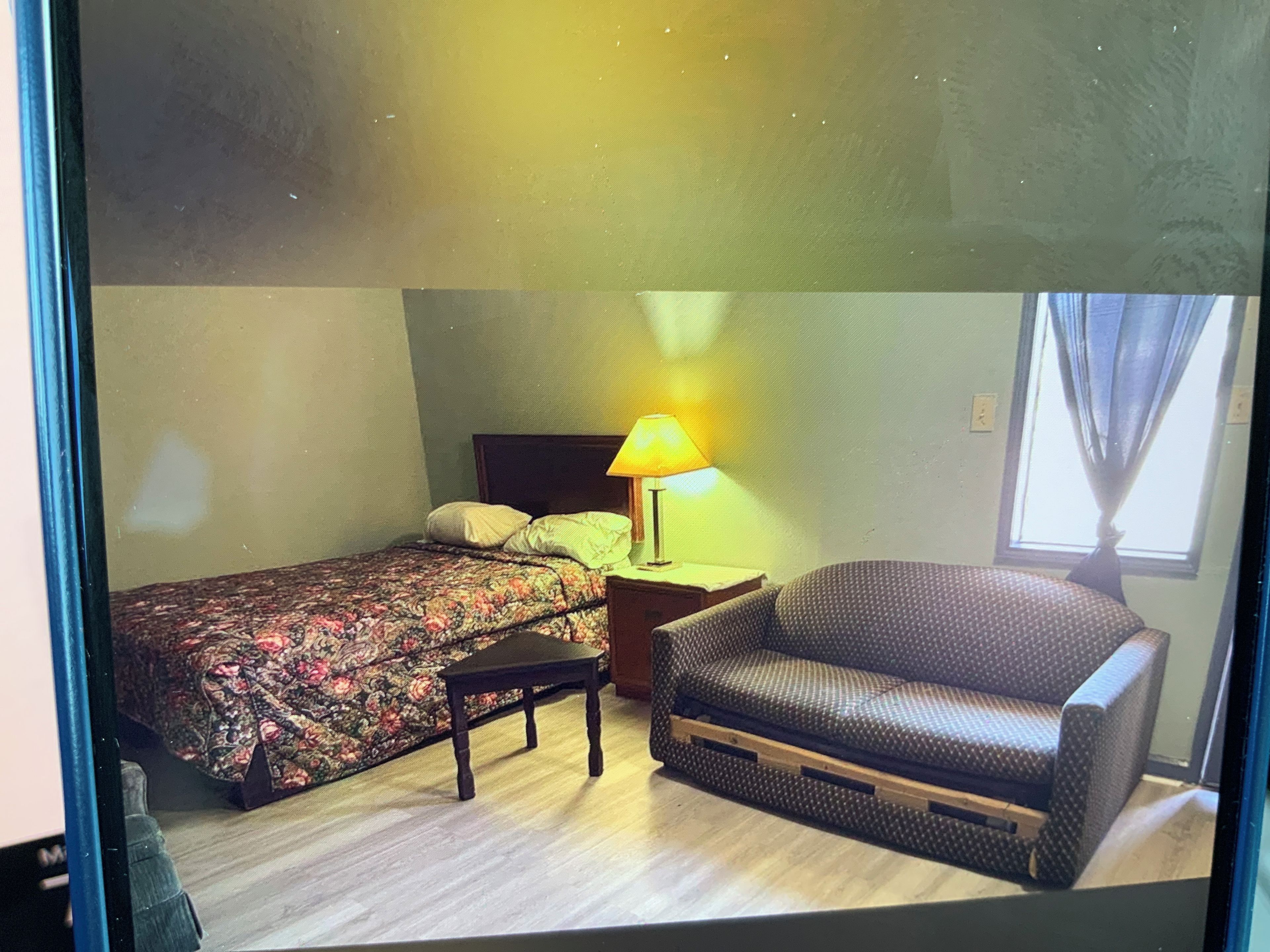 Een kamer met een bed, een stoel, een nachtkastje en een lamp.