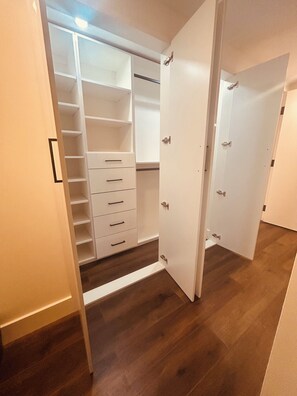 Un armario con puerta abierta, suelo de madera y interior blanco.