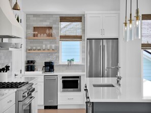 A modern kitchen with white cabinetry, stainless steel appliances, and a window with a view. - The Golden Palms at St. Augustine (St. Augustine)