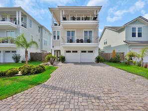 A two-story residential building with a paved driveway, a garage, and a fenced backyard. - The Golden Palms at St. Augustine (St. Augustine)