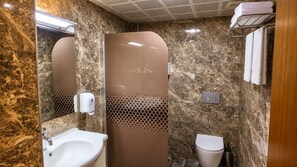 Un bagno con parete in marmo, lavandino, servizi igienici e cabina doccia.