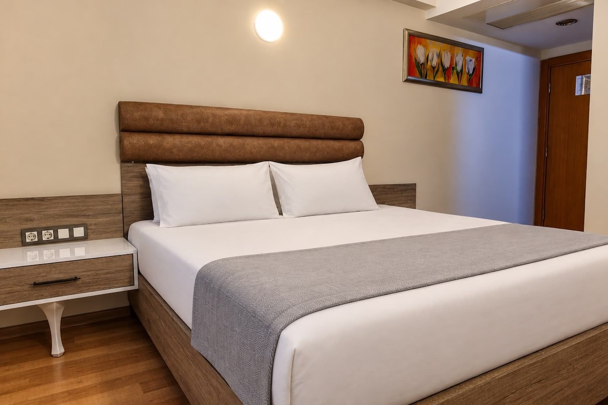 Una camera d'albergo con un letto, un comodino e un quadro appeso al muro.