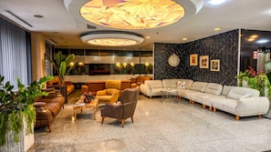Una moderna hall d'hotel con un'area salotto, un grande orologio a parete e decorazioni murali.