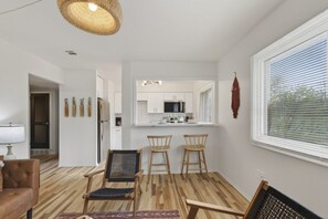 A modern kitchen with white cabinets, a central island, and a dining area with three wooden chairs. - Cozy Stylish Apt in Omaha`s Medical District! (Omaha)