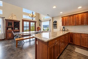 Una cocina amplia con gabinetes de madera, encimera de granito y vista al exterior.
