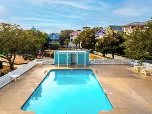 A swimming pool with a white fence, a small gazebo, and colorful houses in the background. - Seaglass Grove (Kure Beach)