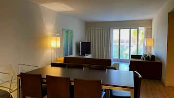 Une chambre d’hôtel équipée d’une table à manger, de chaises, d’un téléviseur et d’un canapé.