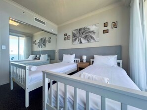 A hotel room with two beds, a large window, a mirror, and artwork on the wall. - Azure 41 Level 41 Ocean Views, Surfers (Surfers Paradise)