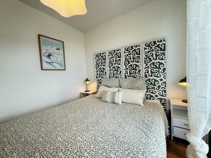 A bedroom with a bed, a nightstand, a lamp, a framed picture, and a decorative wall panel. - Bel appartement avec terrasse et garage - vue pistes (Péone)