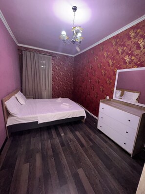 A bedroom with a bed, a dresser, a mirror, a chandelier, and a window with curtains. - Cozy 2-bedroom apartment in fabulous Yerevan centre (Yerevan)