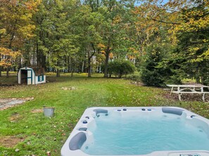 Ein Garten mit Whirlpool, Gartenhaus und Picknicktisch.