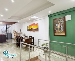 Un comedor espacioso con techo alto, una escalera y una pared verde decorativa.