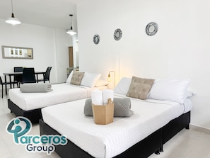 Una habitación de hotel moderna con dos camas, un escritorio y una zona de comedor.