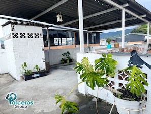 Zona exterior coberta amb plantes en testos, una escultura de metall amb forma de ocell i una paret blanca amb motius decoratius tallats.