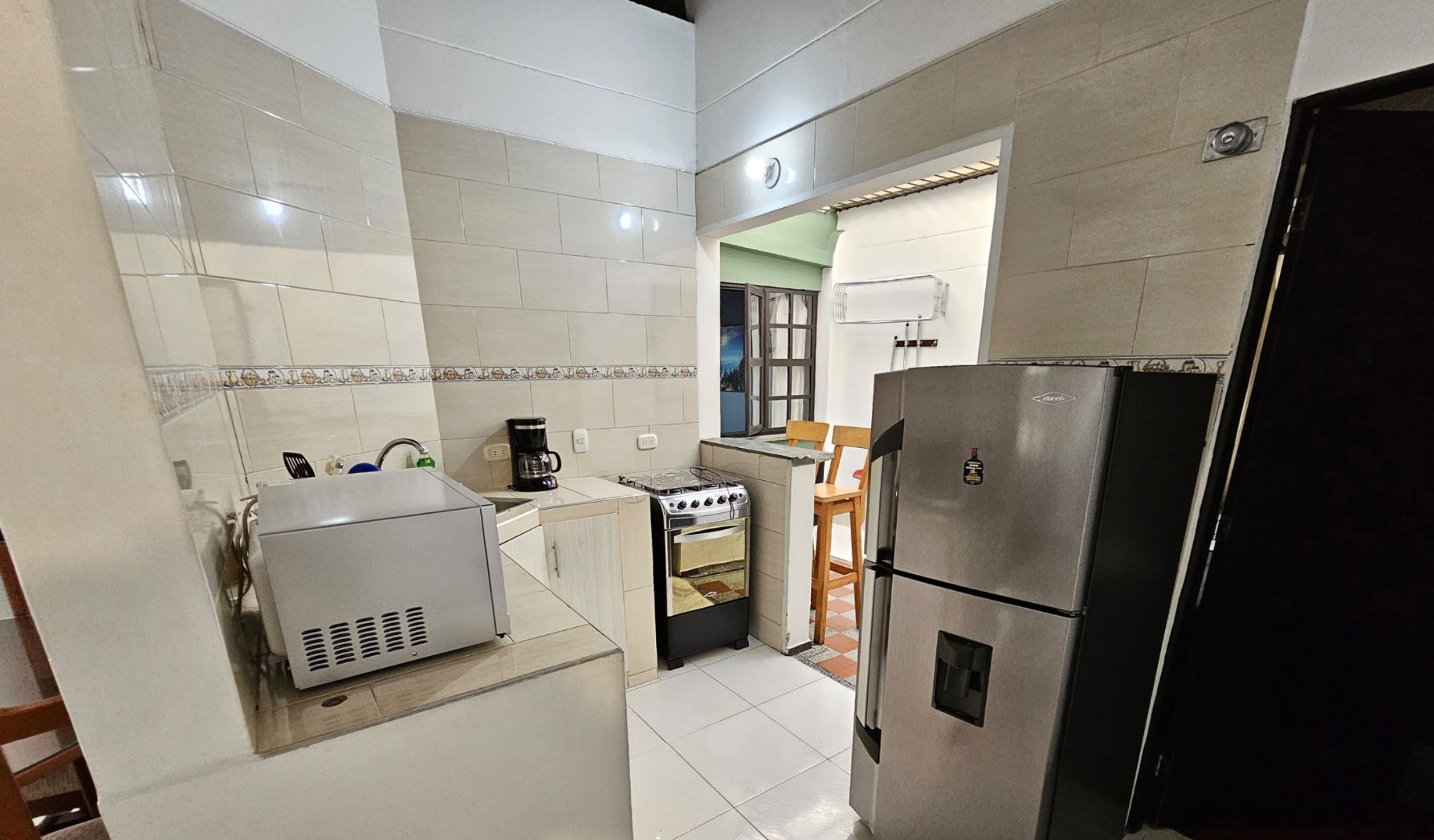 A compact kitchen with a refrigerator, stove, and coffee maker.