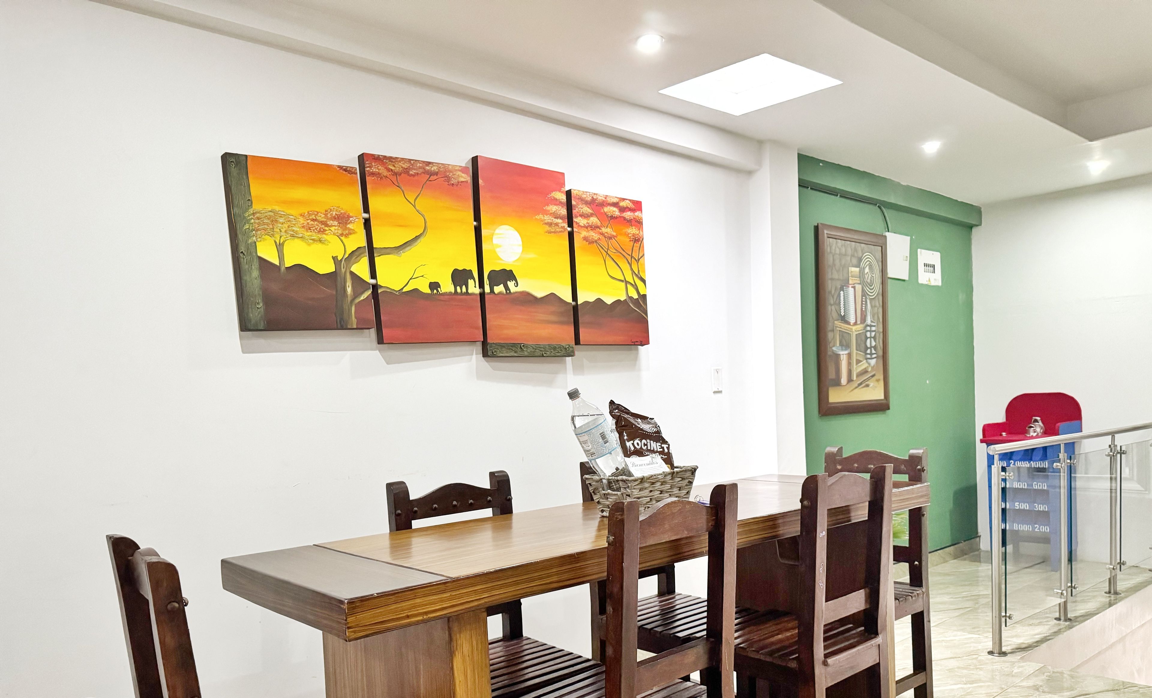 Un comedor con una mesa y sillas de madera, un cuadro en la pared y una puerta verde.