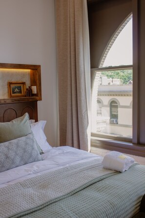 Un llit amb vista a un edifici a través d'una finestra.