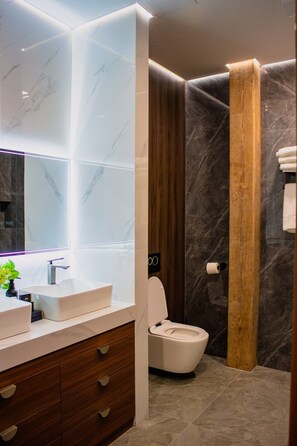 Ein modernes Badezimmer mit Waschtisch aus Marmor, Toilette und Duschbereich.
