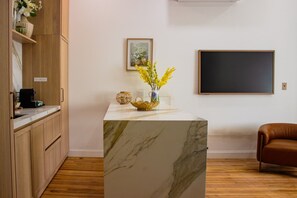 A modern kitchen with wooden cabinets, a marble island, and a coffee machine. - The Ilium Suite 302 - River view Luxury Studio in Downtown Troy (Troy)