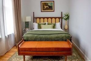 A bedroom with a bed, a bench, a lamp, a picture on the wall, and a window with curtains. - The Ilium Suite 302 - River view Luxury Studio in Downtown Troy (Troy)