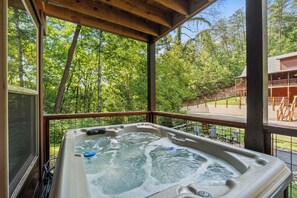 Een hottub met een houten terras en uitzicht op een bebost gebied.
