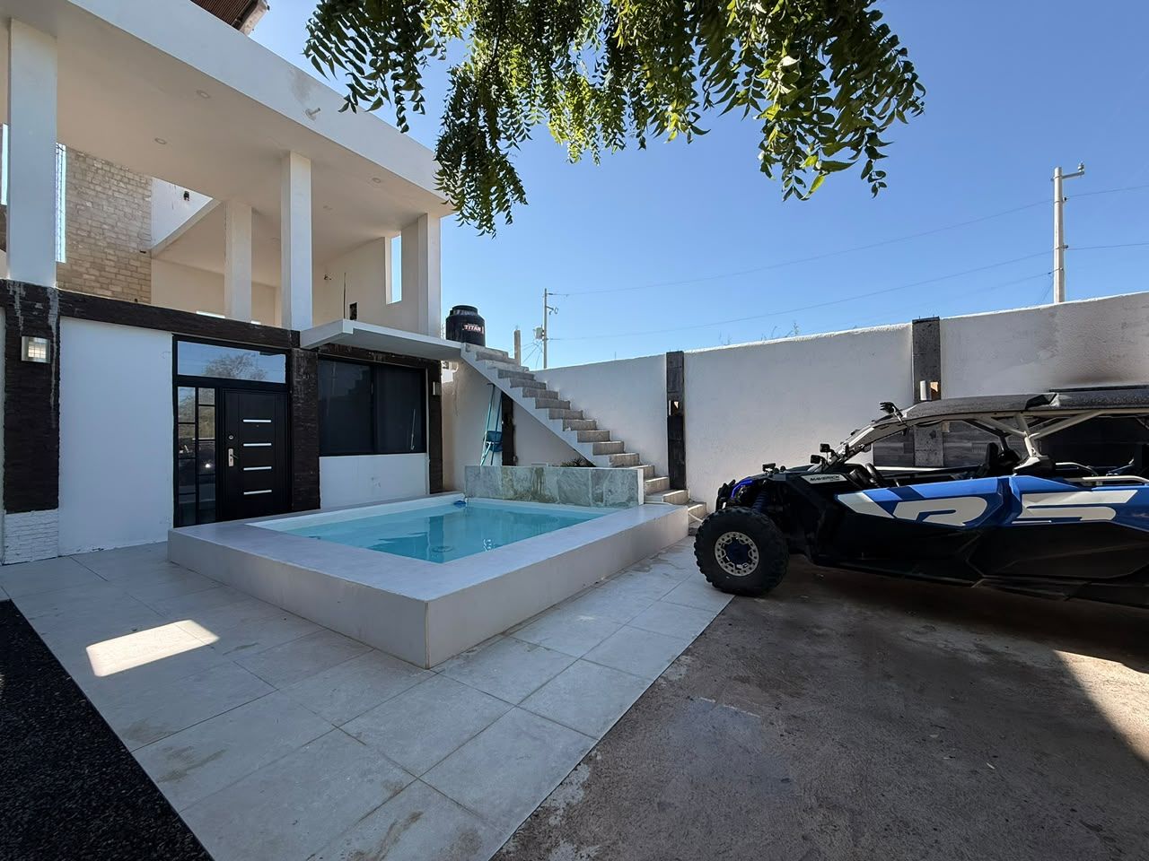 Une maison moderne dotée d’une piscine, d’un escalier et d’un véhicule tout-terrain garé à proximité.