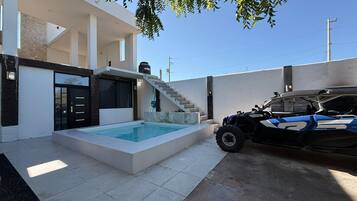 Une maison moderne dotée d’une piscine, d’un escalier et d’un véhicule tout-terrain garé à proximité.