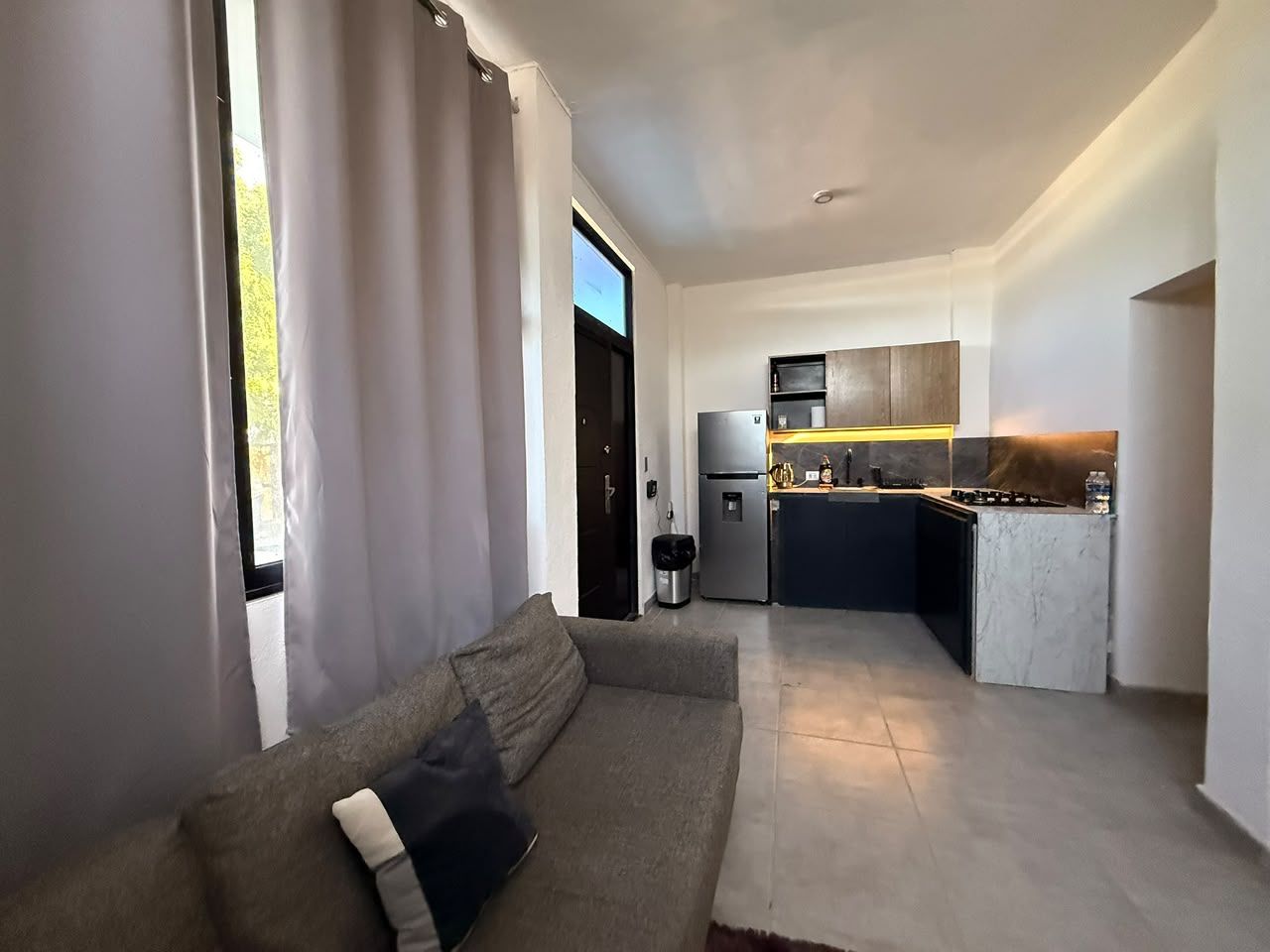 Un salon moderne avec un canapé et une vue sur la cuisine.
