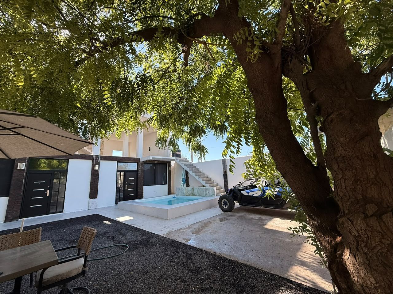 Uma área externa moderna com piscina, assentos e escadaria que leva a um edifício.