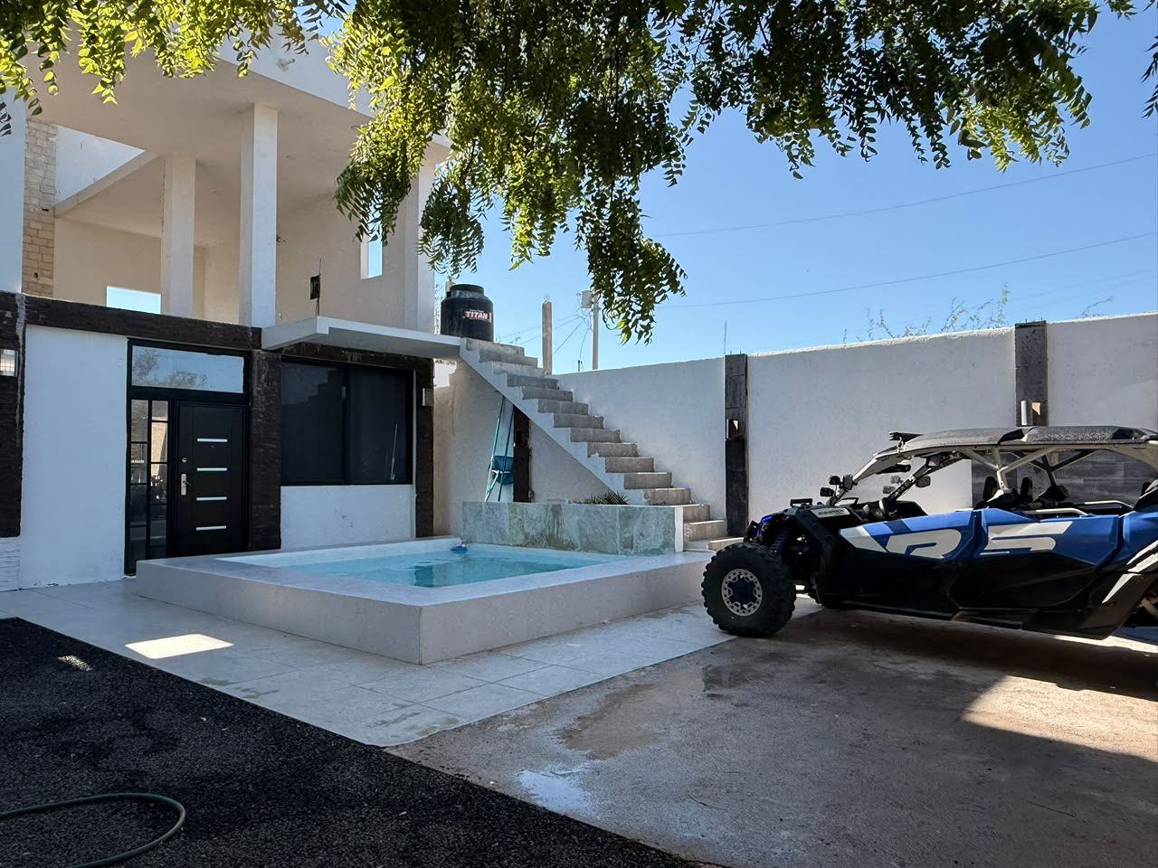 A modern house with a swimming pool, a staircase, and a quad bike parked outside.
