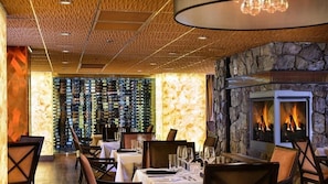 A restaurant interior with a stone wall, a fireplace, and a wall of wine bottles. - Westgate Park City 4BR Villa - Private Hot Tub Balcony, Ski-In/Ski-Out (Park City)