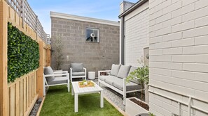 A patio with a white table, two white chairs, and a grey sofa. - 10 Hobson - Coastal Retreat (Queenscliff)