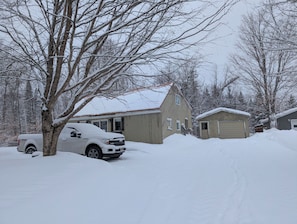 A residential area with a house, a garage, and a snow-covered driveway.