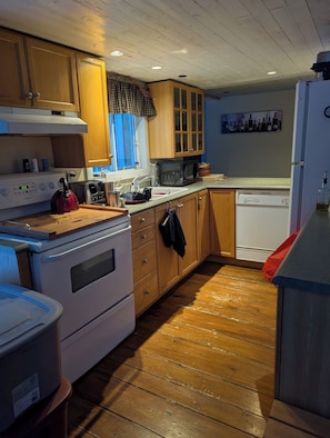 A kitchen with wooden cabinets, a stove, a microwave, and a dishwasher.
