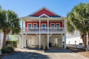 A two-story house with a red facade, white balcony railings, and a covered porch area. - Hot Dogs in Paradise - Carolina Beach Getaway (Carolina Beach)