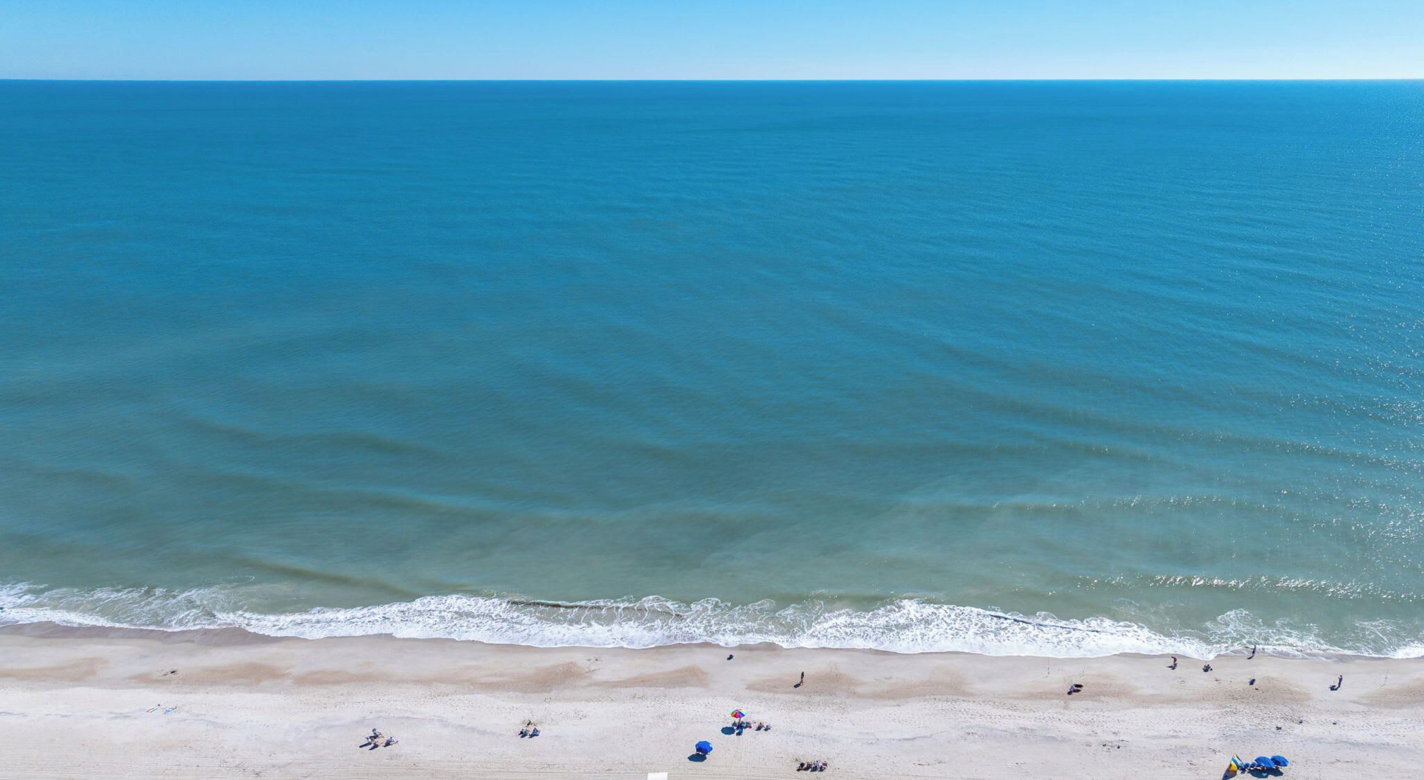 A beach with a clear view of the ocean and a sandy shore.