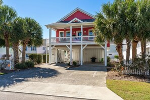 A two-story house with a red and white exterior, a covered front porch, and a garage. - Hot Dogs in Paradise - Carolina Beach Getaway (Carolina Beach)