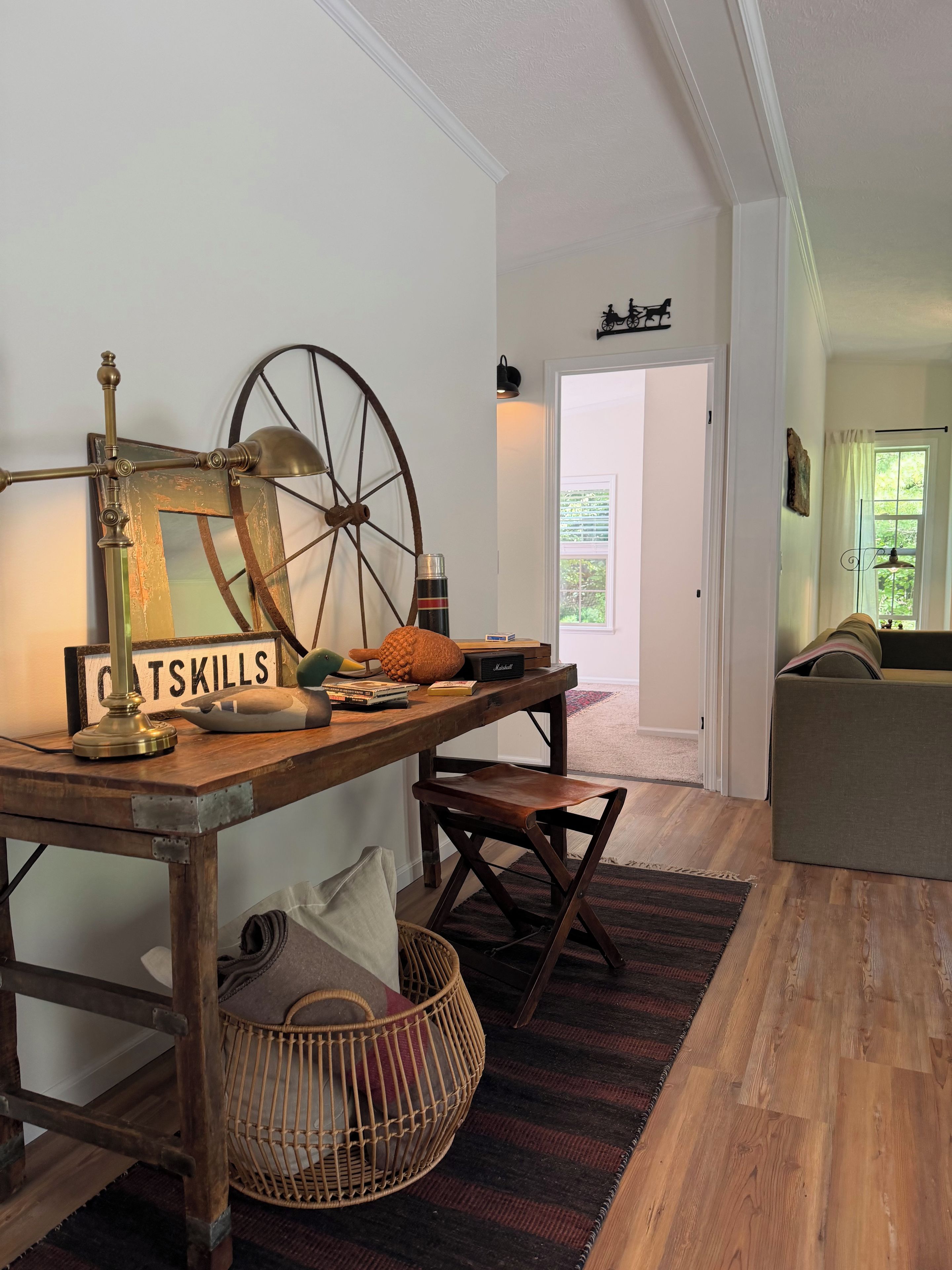 A cozy living room with a wooden table, a vintage lamp, and a large wheel chair.