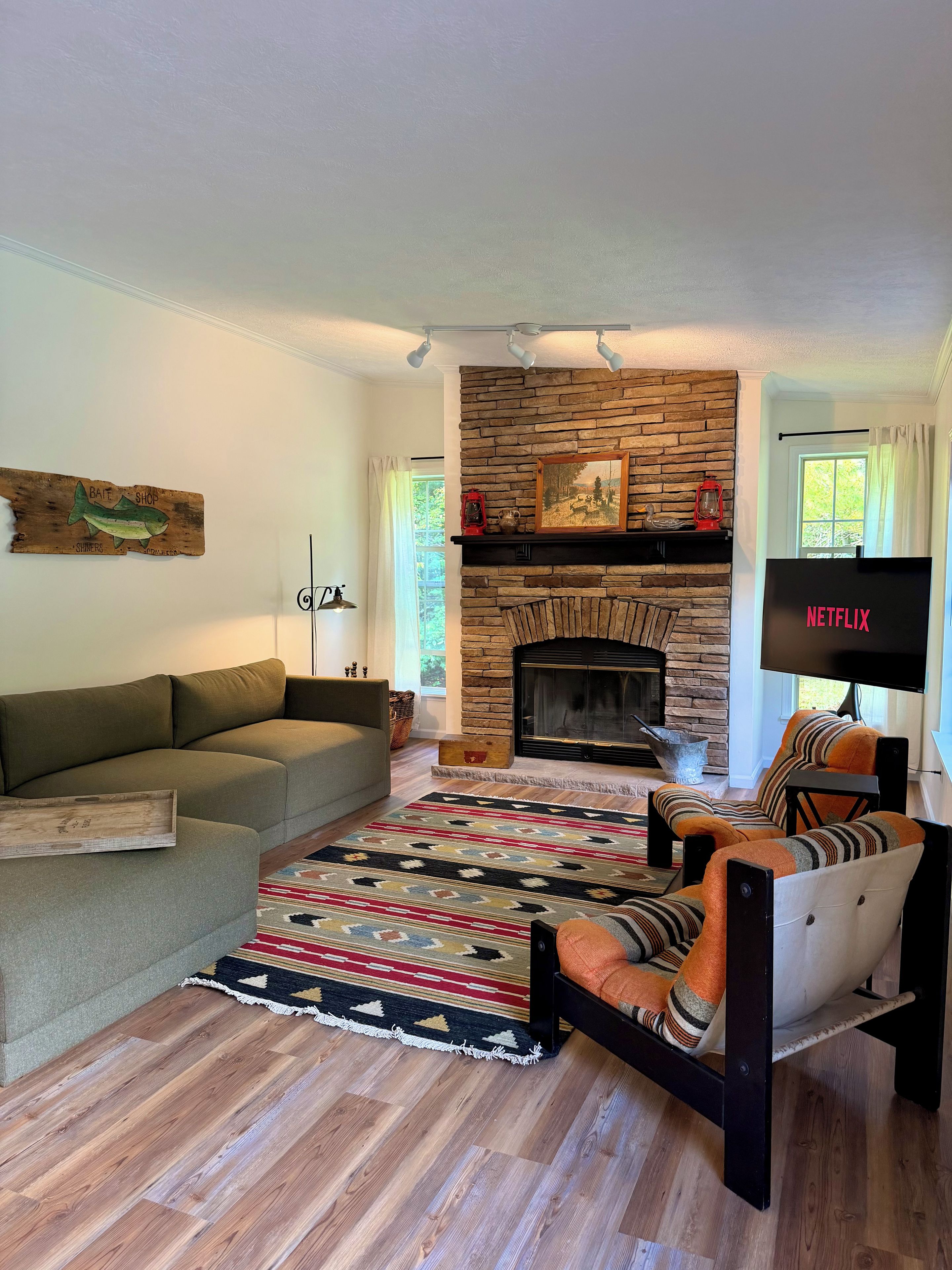 A living room with a stone fireplace, a sofa, a patterned rug, and a television.