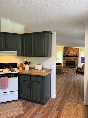 A kitchen with dark cabinets, a white stove, and a toaster on the counter. - The Mountain Pond View Retreat in the Catskills (Gilboa)