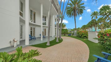 A hotel with a curved brick pathway, palm trees, and outdoor seating.